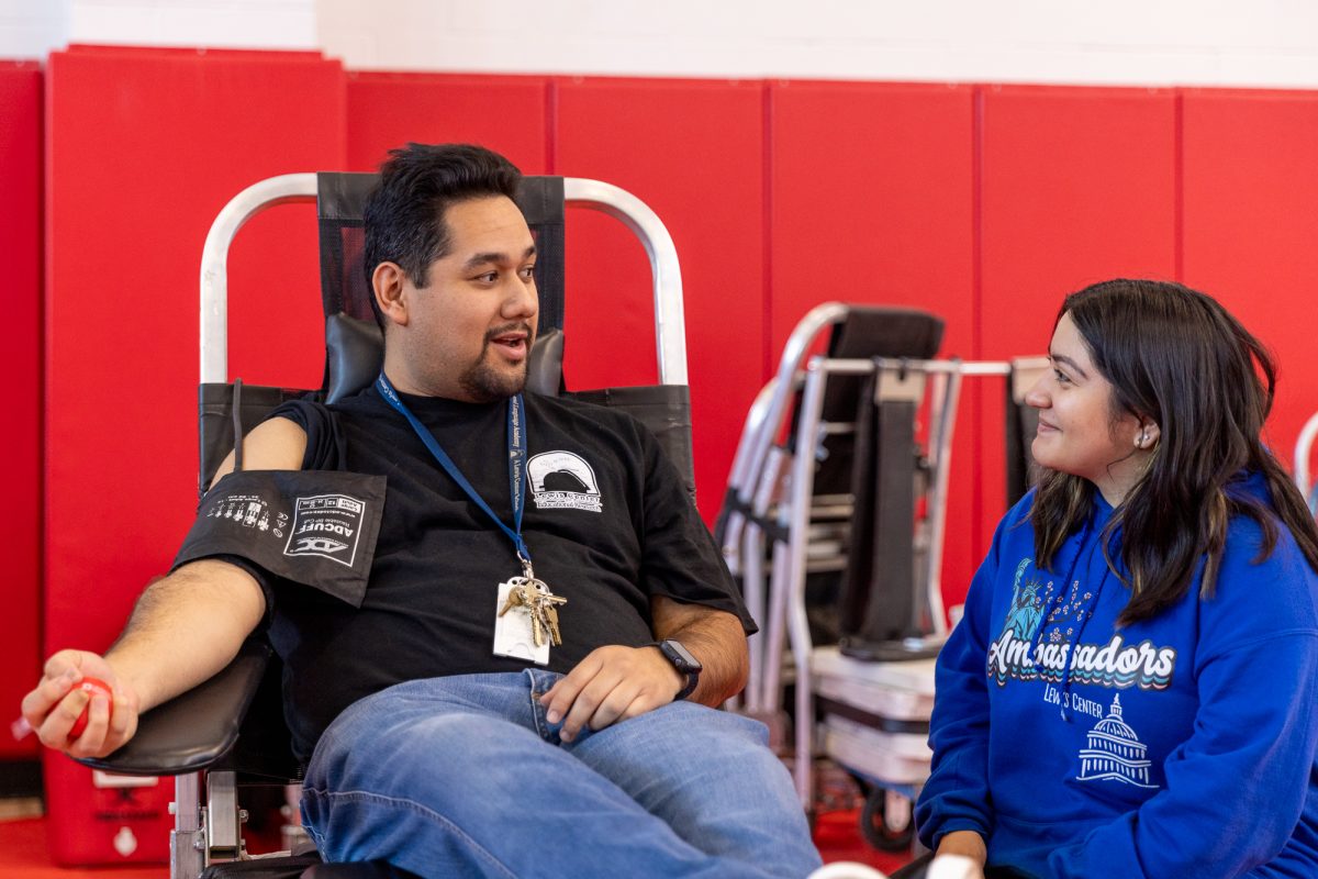 High school computer science teacher Daniel Ruiz talks to Norton Ambassador Kasey Medina ('25) while he donates blood. (Photo credit: Ellis Evans)