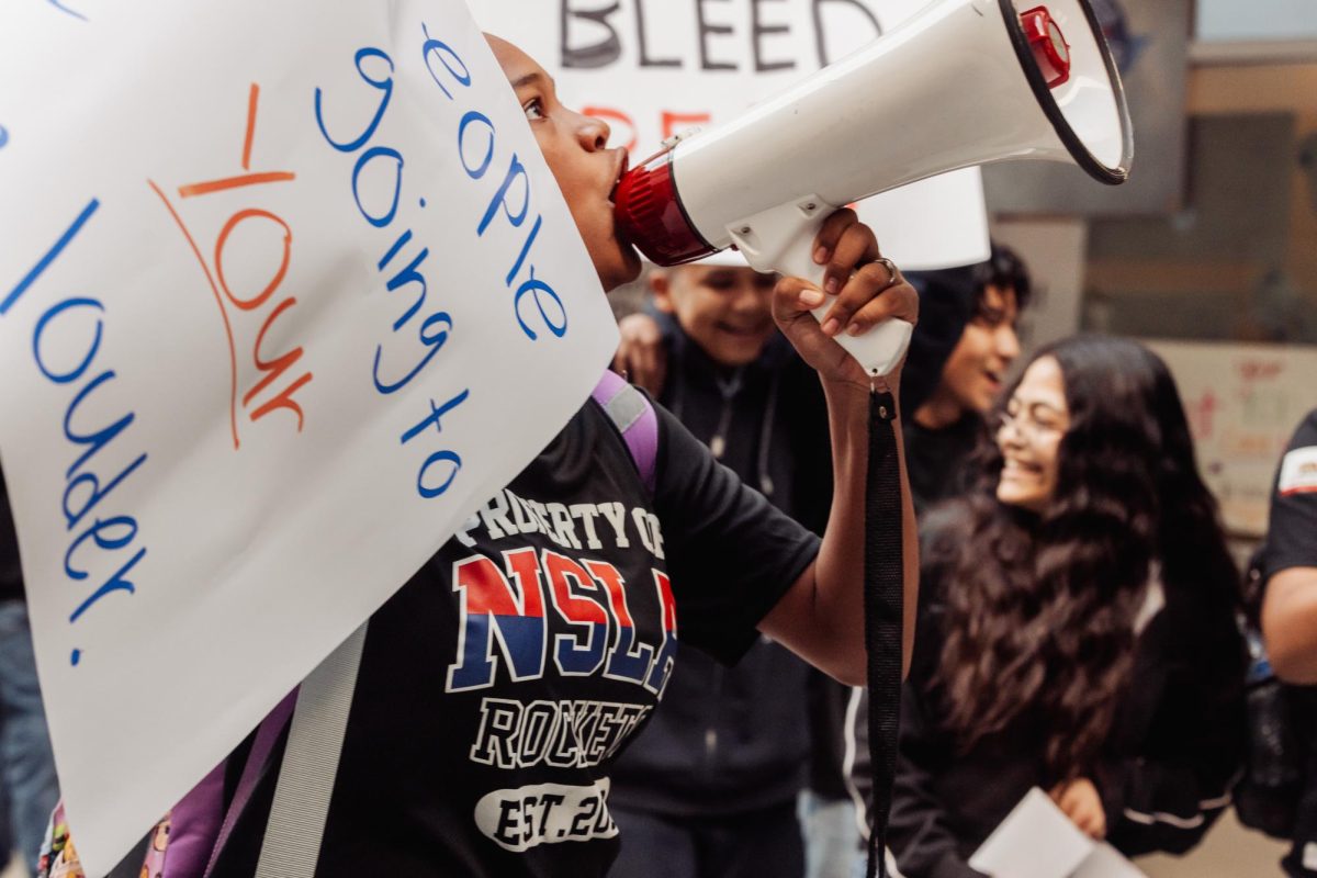 Eighth grader Mia Youngblood marches out of class holding megaphone and poster on Friday, Feb. 6, 2026 to protest Immigration and Customs Enforcement (I.C.E.) operations and some political leaders' pushback against student-led protests. The protest marked Norton's second student-led protest in the last month, following the nationwide increase in youth activism after the "National Shutdown" on Jan. 30, 2026. (Photo credit: Betsy Ramirez)


